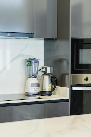 Een keuken met een blender, waterkoker en een magnetron op een marmeren aanrecht.