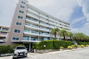 A multi-story hotel with balconies, a paved driveway, and a car parked in front. - Best Seaview 1 Bed Condo Sky Garden Rawai Beach (Rawai)