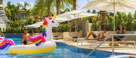 A swimming pool with inflatable unicorn floats, lounge chairs, and umbrellas.