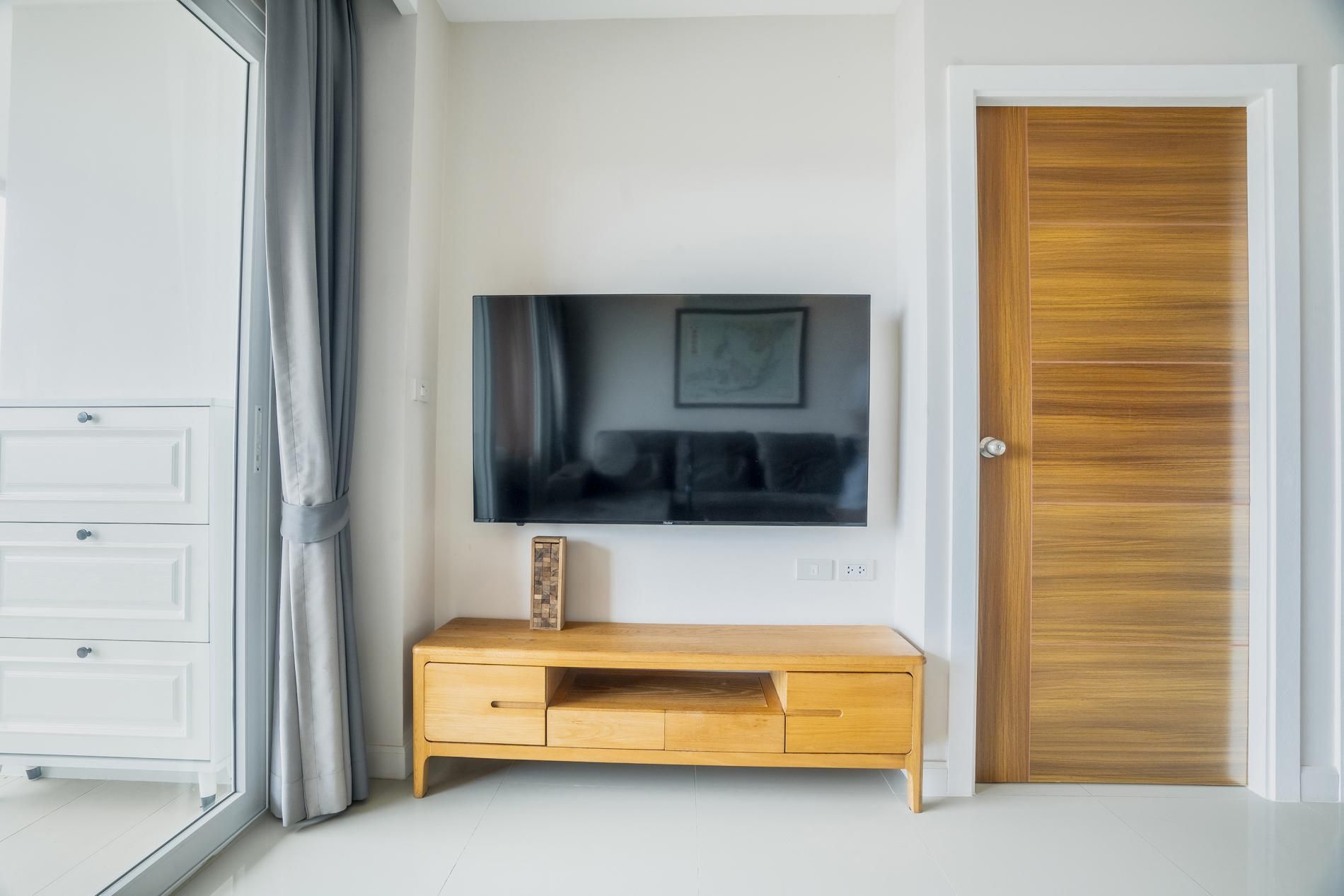 Ein Zimmer mit einem Holzkasten, einem flachbildfernseher an der Wand und einer Holztür.