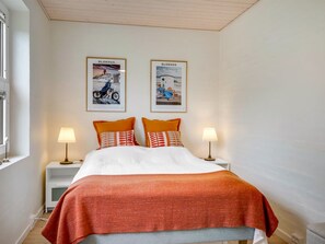 A bedroom with a bed, two pillows, two bedside tables with lamps, and two framed pictures on the wall. - "Helemine" - 800m from the sea by Interhome (Blokhus)
