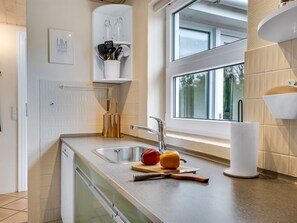 A modern kitchen with a double sink, a window, and a countertop with a cutting board, a knife, and a red and yellow bell pepper. - "Helemine" - 800m from the sea by Interhome (Blokhus)