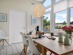 Een moderne eethoek met een houten tafel, witte stoelen en een decoratieve lamp.