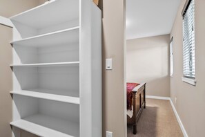 A hallway with a white shelving unit and a small table with a red cloth. - Modern 2-bedroom Container Home with beautiful river views (Canby)
