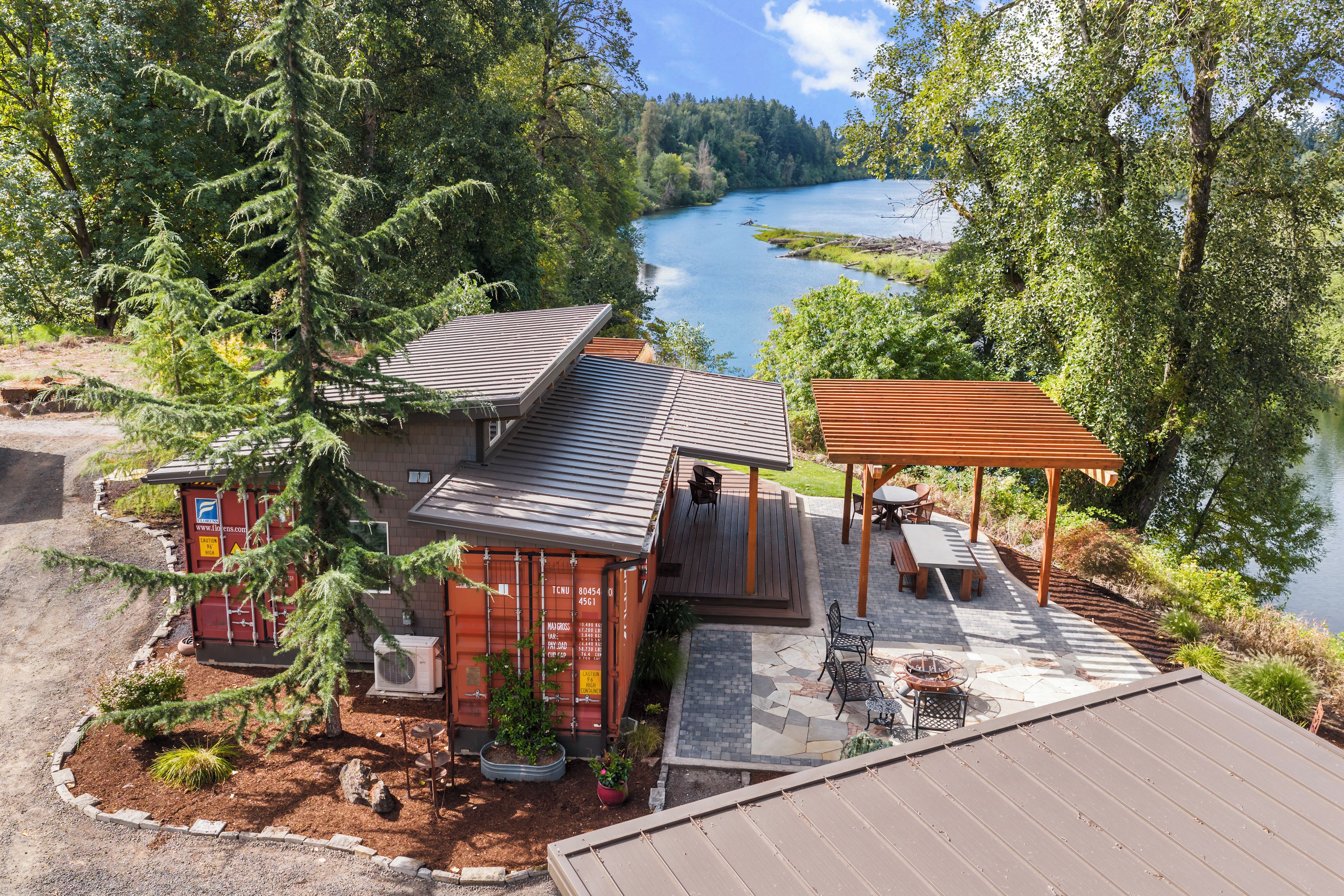 A cabin with a deck overlooking a lake, surrounded by trees.