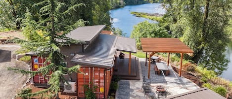 A cabin with a deck overlooking a lake, surrounded by trees.