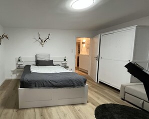 A bedroom with a bed, a wardrobe, a desk, and a wall-mounted deer head. - Guest Rooms Eifelgluck in Pelm (Pelm)