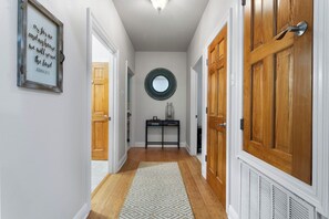 Un couloir avec des portes en bois, un miroir, une citation encadrée et un tapis à motifs.