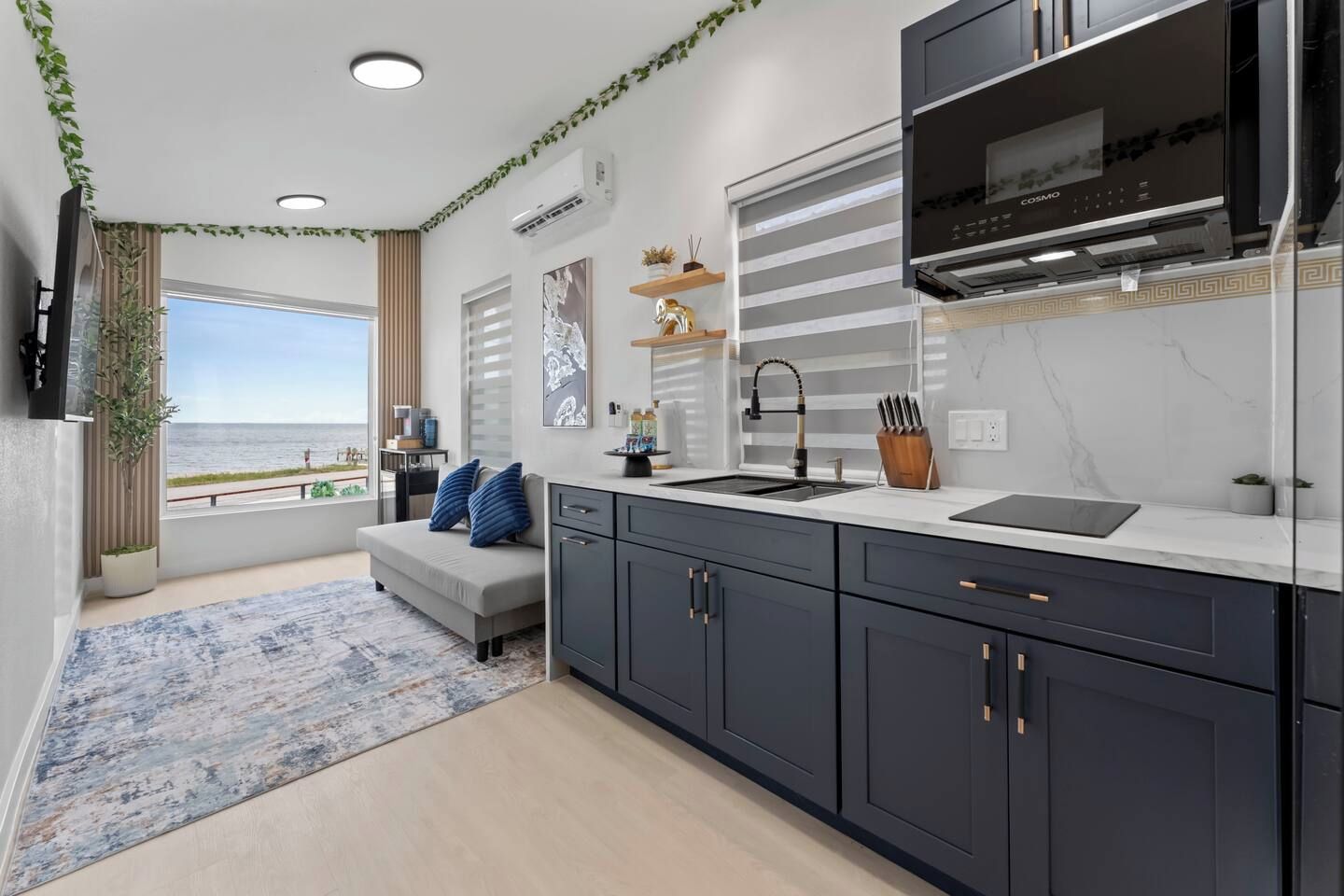 A modern kitchen with a large window, a built-in oven, and a flat-screen TV.