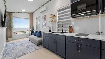 A modern kitchen with a large window, a built-in oven, and a flat-screen TV.