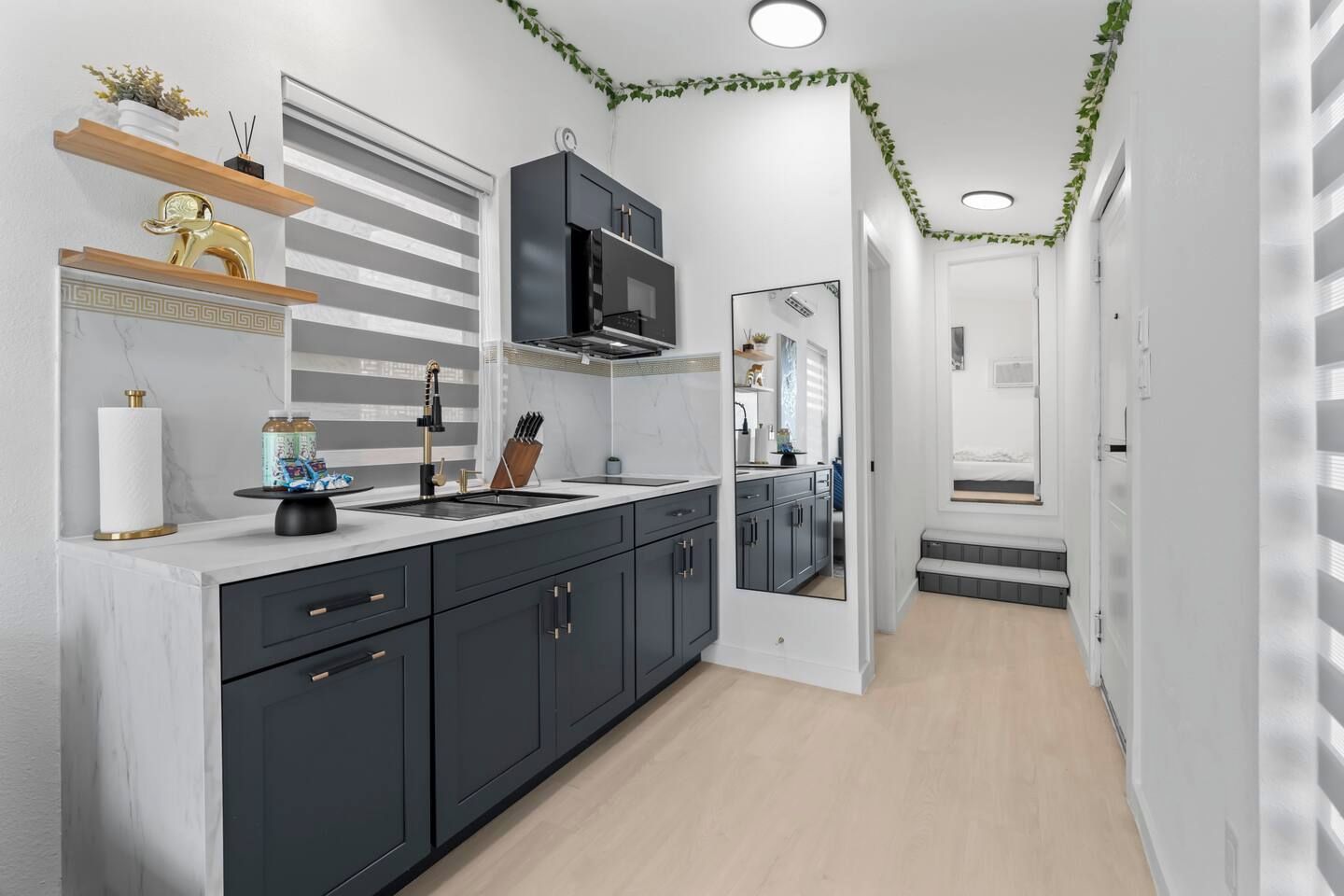 A modern kitchen with dark cabinetry, a central island, and a built-in oven.