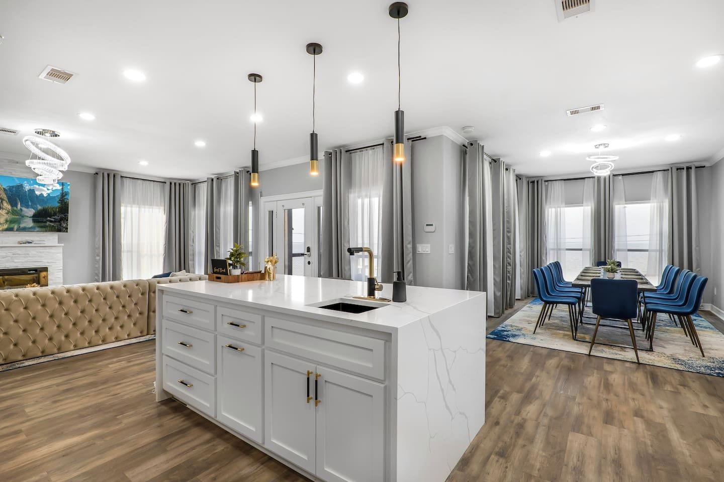 A modern kitchen with a marble countertop, a built-in oven, and a dining area with blue chairs.