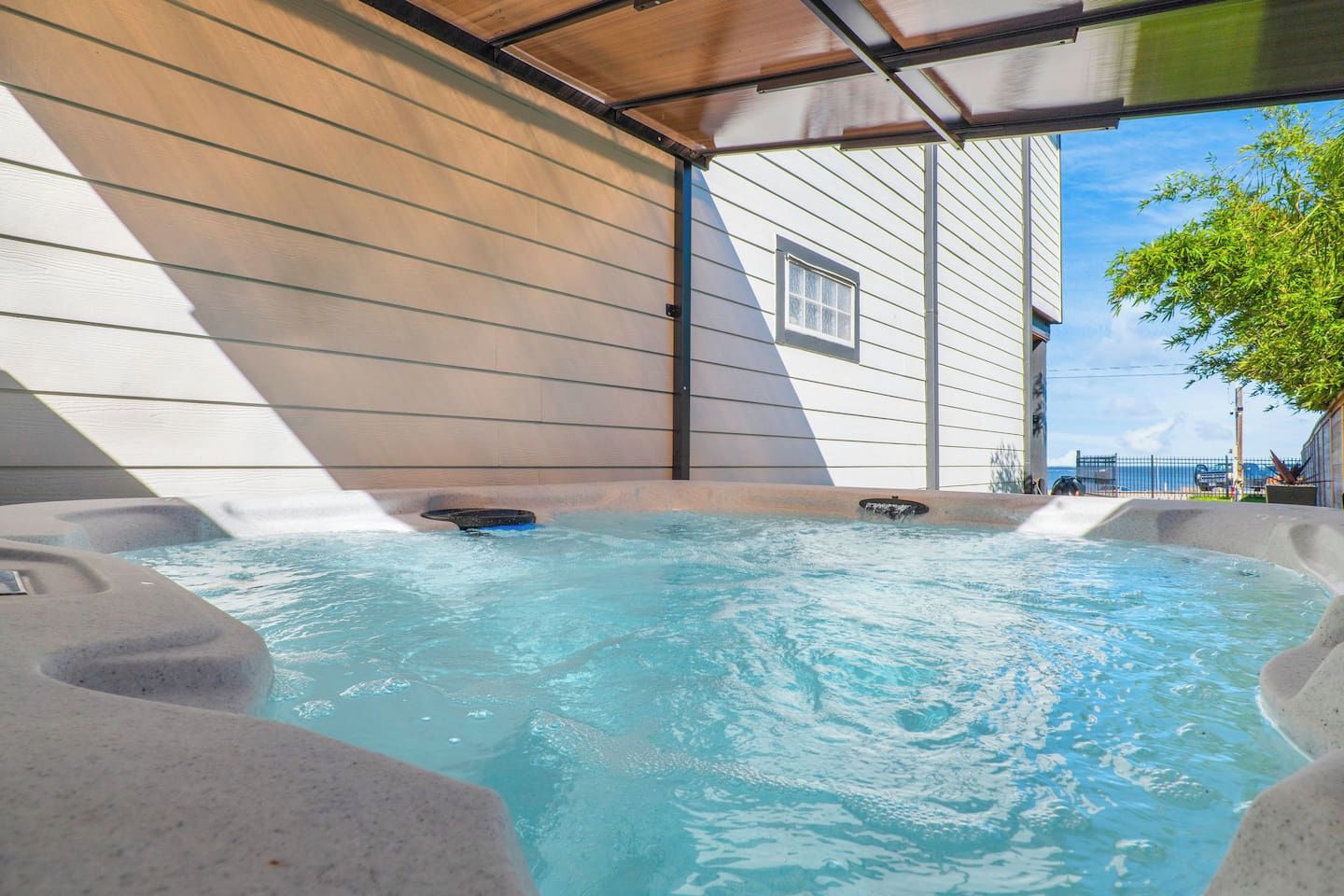 A hot tub area with a view of a building and a tree.