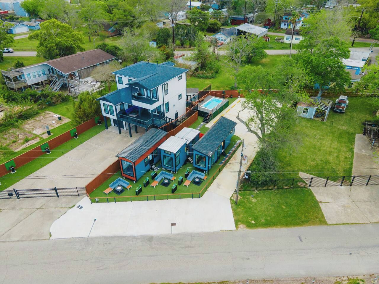 A modern two-story building with a swimming pool, outdoor seating, and a covered patio area.