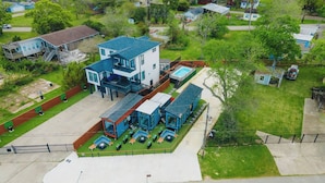 A modern two-story building with a swimming pool, outdoor seating, and a covered patio area. - Palme Bayfront Estate | 4 Homes, Pool + Hot Tub (Bacliff)