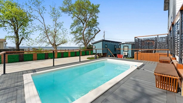 A swimming pool with a wooden deck, a small building, and a view of the sea. - Palme Bayfront Estate | 4 Homes, Pool + Hot Tub (Bacliff)