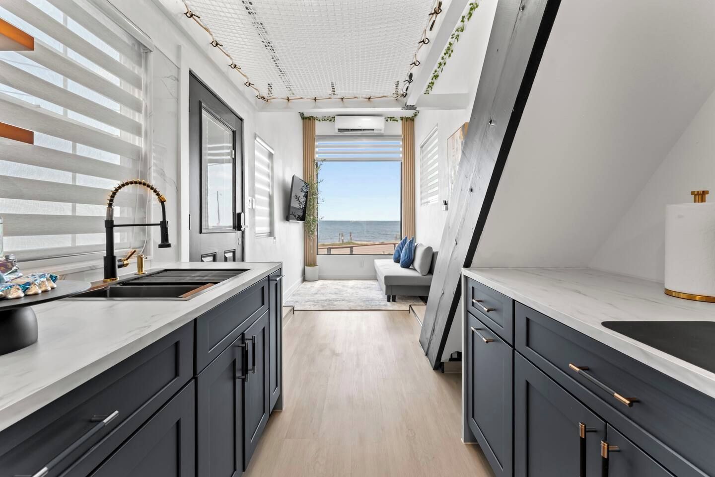A modern kitchen with a large window, a built-in oven, and a view of the sea.