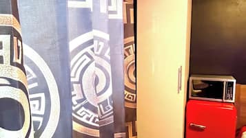 A room with a patterned curtain, a white door, and a red appliance.