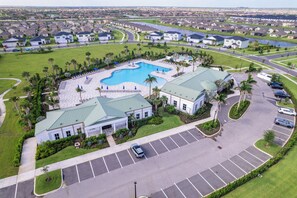 Ett bostadsområde med en swimmingpool, en parkeringsplats och en stor byggnad med ett grönt tak.