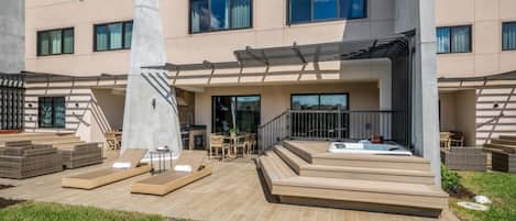 A modern building with a patio area, outdoor seating, and a hot tub.