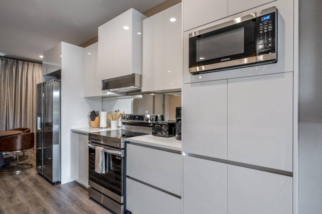 A modern kitchen with white cabinetry, stainless steel appliances, and a built-in microwave.