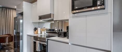 A modern kitchen with white cabinetry, stainless steel appliances, and a built-in microwave.