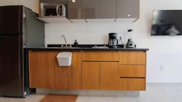 Una cocina moderna con microondas integrado, cafetera y licuadora sobre la encimera.