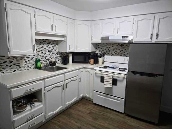 A kitchen with white cabinets, a microwave, a stove, and a refrigerator.