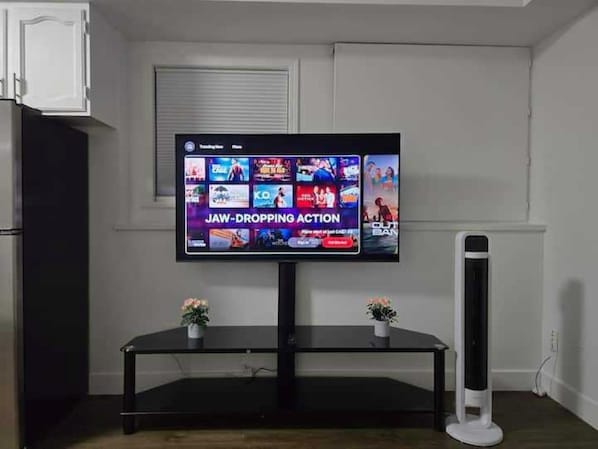 A flat-screen TV mounted on a wall with a black entertainment center below.