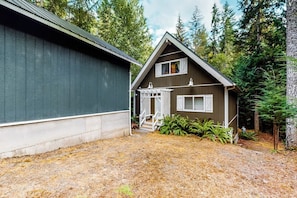 A two-story cabin with a porch and a covered entryway, surrounded by a forested area. - Rural 2BR Dog Friendly - Dock - Deck - Firepit (Hoodsport)
