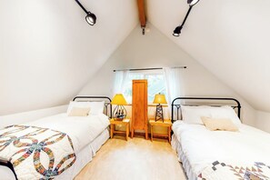 A bedroom with two beds, a wooden floor, a window with curtains, and a wooden ceiling beam. - Rural 2BR Dog Friendly - Dock - Deck - Firepit (Hoodsport)