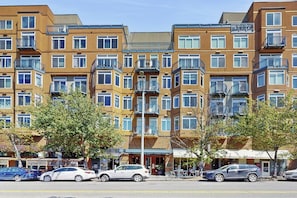 A multi-story residential building with balconies, a street in front, and parked cars. - 1BR Modern Belltown Condo with Free Parking (Seattle)