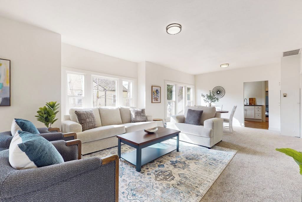A spacious living room with a sofa set, a coffee table, and a patterned rug.