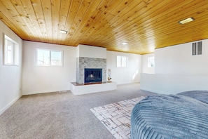 Ein Zimmer mit Kamin, Holzboden und einem gemusterten Teppich.