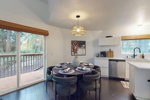 A modern kitchen with a dining area, large windows, and a deck. - 1 BR with loft, hot tub, & sauna (Gig Harbor)