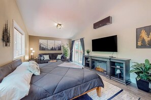 A bedroom with a large bed, a TV, a fireplace, and a window. - 2BR riverfront gem with kayaks & hot tub - dogs ok (Tahuya)