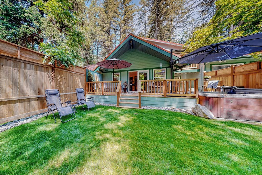 Une terrasse en bois avec un espace couvert, un barbecue et une cour arrière clôturée.
