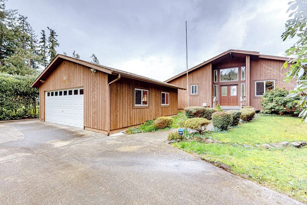 A two-story wooden house with a garage and a front porch.