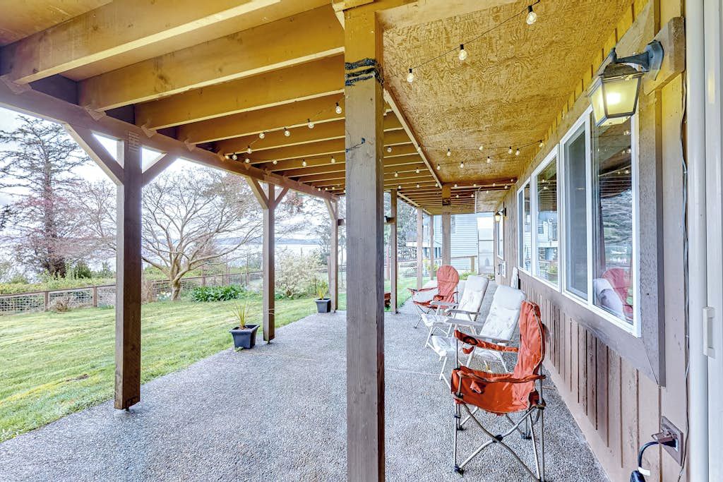 Un espacio al aire libre cubierto con piso de grava, vigas de madera y una fila de sillas.