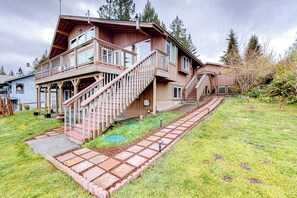 Une maison en bois à deux étages, dotée d’un balcon et d’un escalier menant à l’étage supérieur.