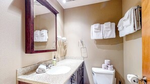 A bathroom with a sink, mirror, toilet, and towels. - 1BR with fireplace and Puget Sound and Mt. Baker views (Port Ludlow)
