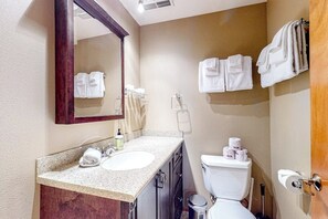 Une salle de bain équipée d’un lavabo, d’un miroir, de toilettes et de serviettes.