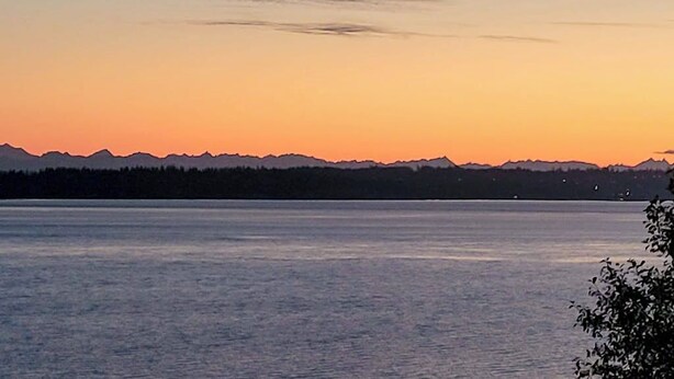 A calm lake with mountains in the distance and a clear sky. - 1BR with fireplace and Puget Sound and Mt. Baker views (Port Ludlow)