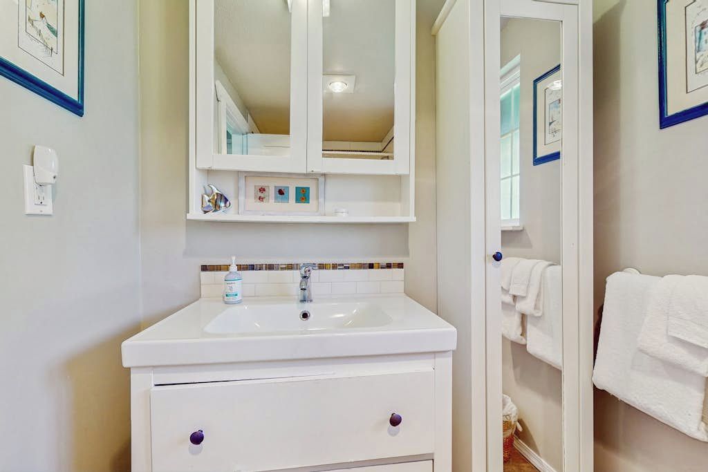 Une salle de bain avec un lavabo blanc, un miroir et un porte-serviettes.