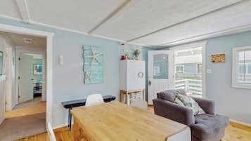 Una habitación con una mesa de comedor de madera, un sofá gris, un armario blanco y una decoración de estrella de mar en la pared.