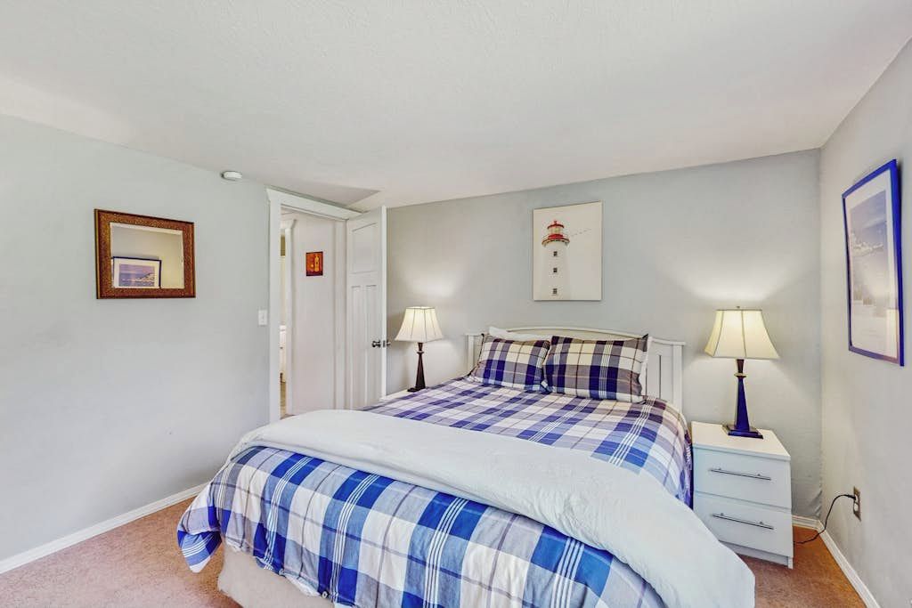 Une chambre à coucher avec un lit, deux tables de chevet, une porte et un tableau accroché au mur.