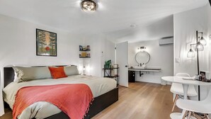 Quarto moderno com cama, mesa de cabeceira e pequeno espaço de escritório.