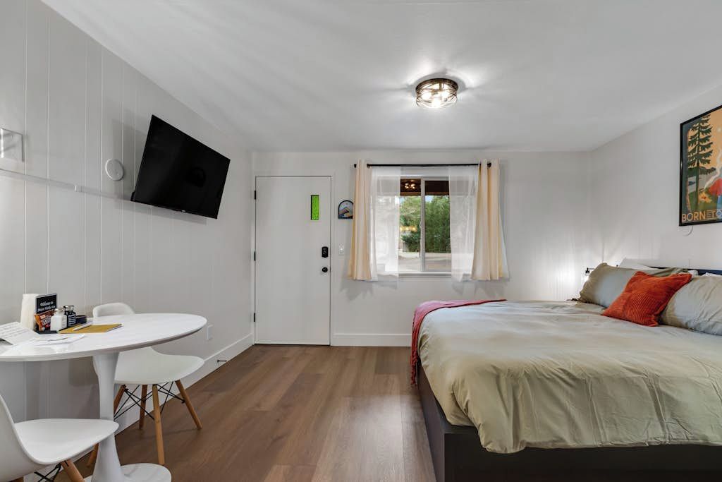 A room with a bed, a desk, and a television on the wall.
