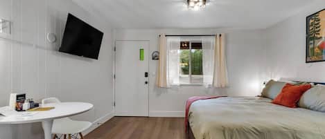 A room with a bed, a desk, and a television on the wall.