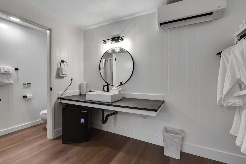 A bathroom with a white sink, mirror, and towel rack.